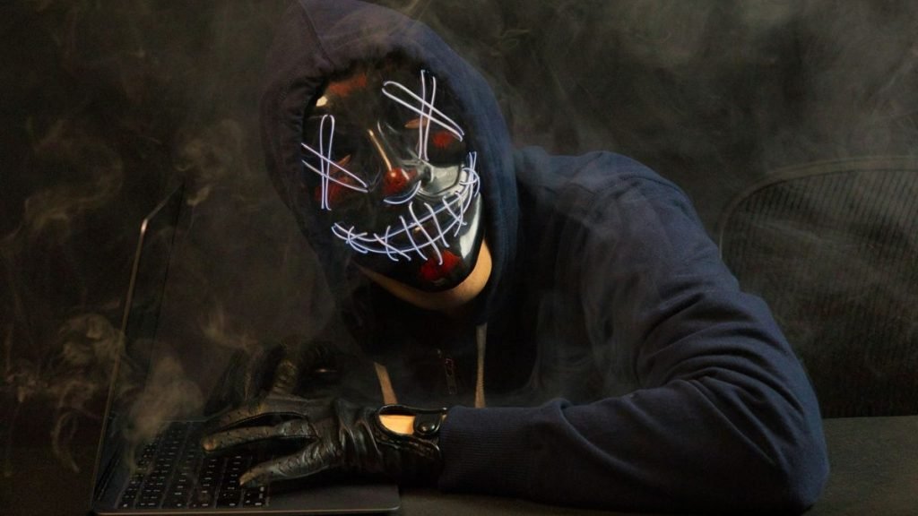 Masked hacker at computer desk