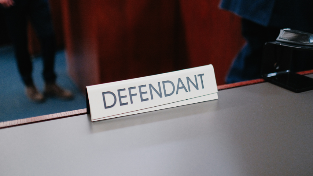 Sign reading "defendant" on desk