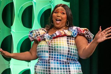 Lizzo singing with raised arms