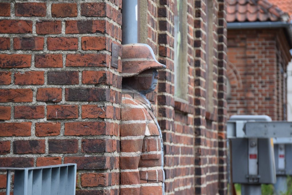 Troll statue beside red brick wall