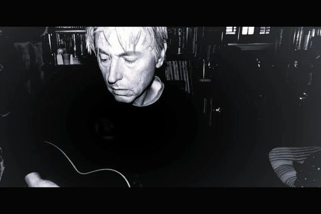 Man strumming guitar in room